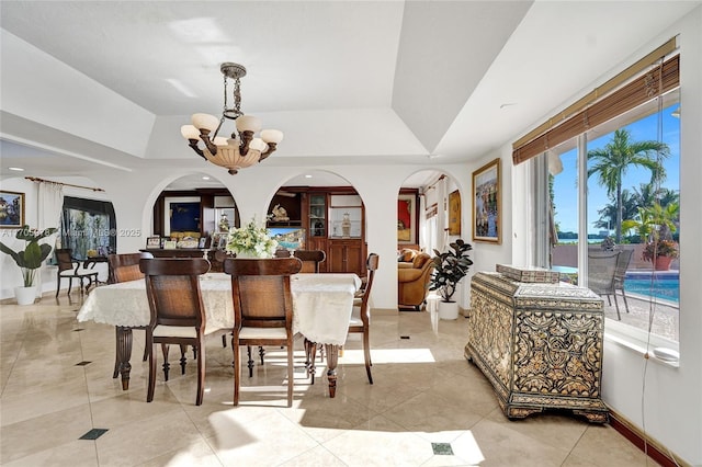 1960 NE 118th Rd, North Miami, FL 33181 - dining space with a chandelier, light tile patterned floors, a tray ceiling, arched walkways, and baseboards
