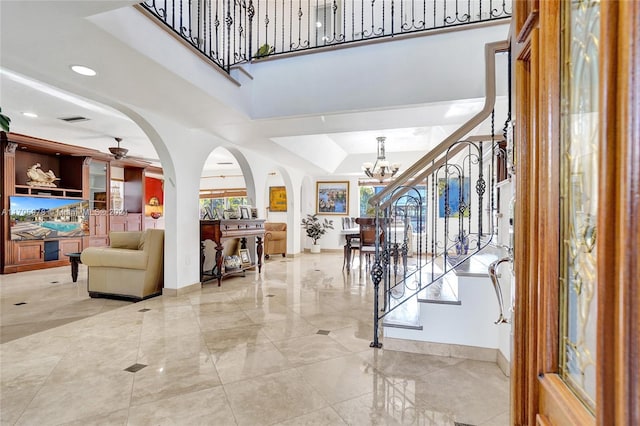 entryway with a tray ceiling and ceiling fan with notable chandelier