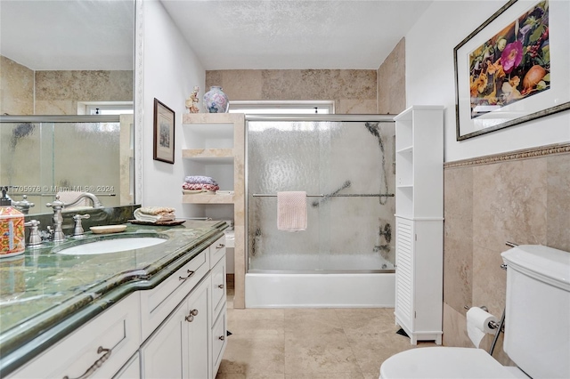 full bathroom featuring enclosed tub / shower combo, tile patterned floors, toilet, vanity, and tile walls