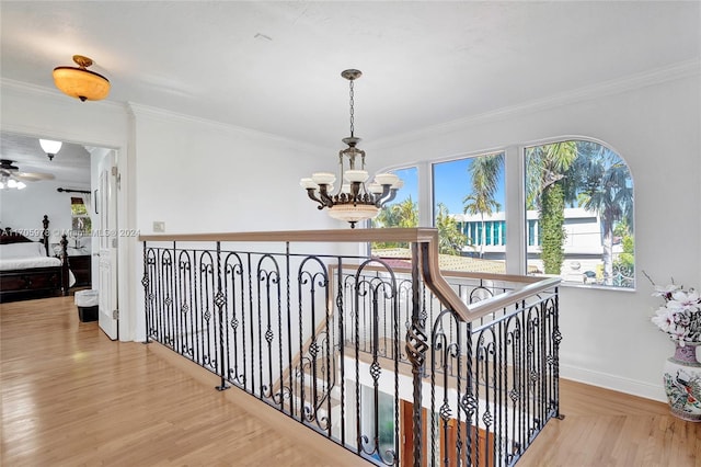 hall featuring light wood-type flooring, an inviting chandelier, and crown molding