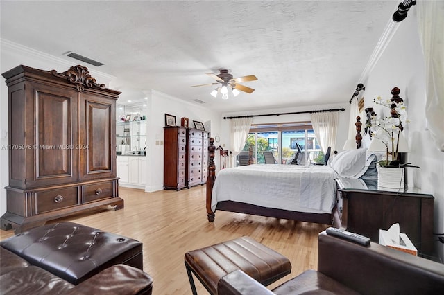 bedroom featuring ceiling fan, light hardwood / wood-style floors, ornamental molding, and a textured ceiling