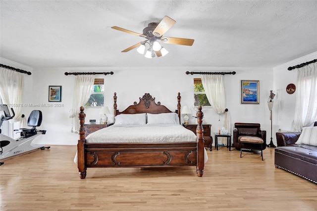 bedroom with a textured ceiling, light hardwood / wood-style flooring, ceiling fan, and crown molding