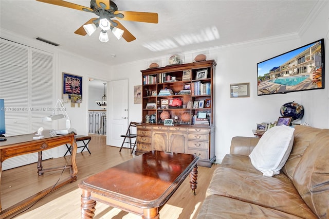 living room with crown molding, ceiling fan, and light wood-type flooring