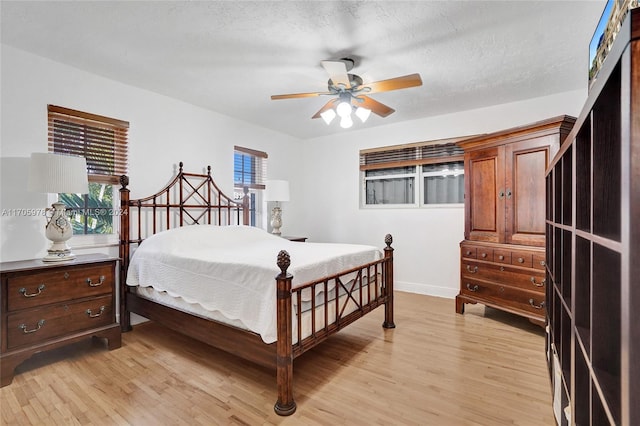 bedroom with multiple windows, a textured ceiling, light hardwood / wood-style floors, and ceiling fan