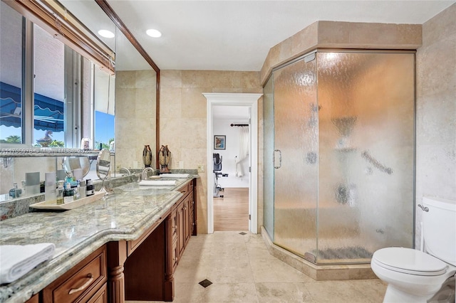 bathroom with vanity, toilet, an enclosed shower, and tile walls