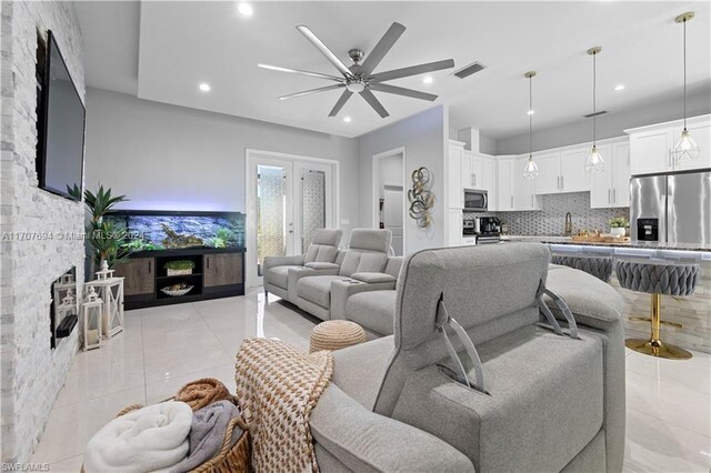 living room featuring light tile patterned floors, french doors, ceiling fan, and sink