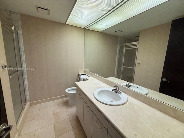 bathroom with tile patterned flooring, vanity, a shower with shower door, and toilet