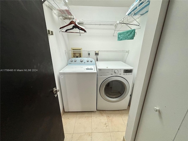 laundry area with washer and dryer and light tile patterned floors