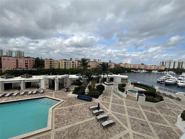 view of pool featuring a patio area, a grill, and a water view