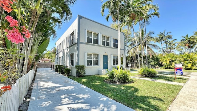 view of front of house with a front lawn, fence, and stucco siding