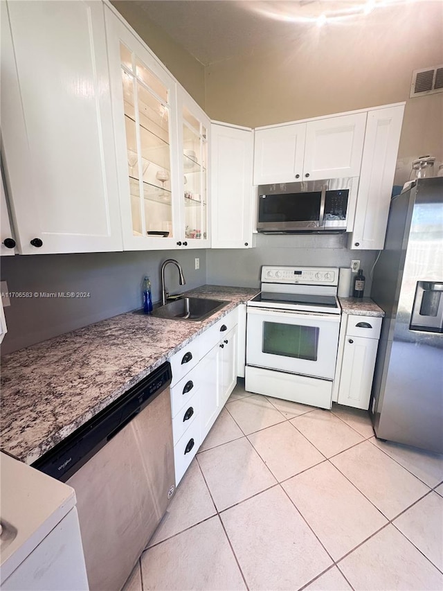 kitchen with white cabinets, stainless steel appliances, light tile patterned flooring, and sink