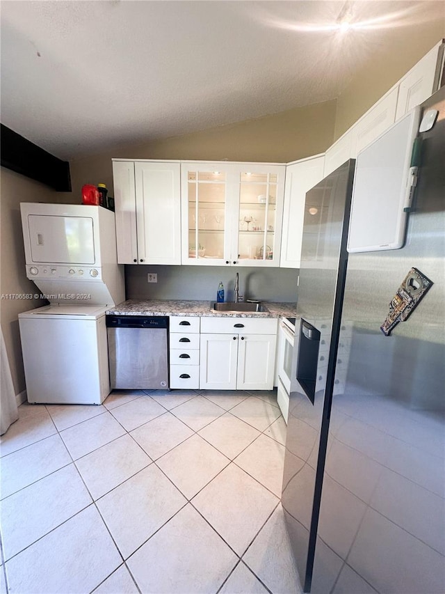 kitchen with white cabinetry, sink, stacked washing maching and dryer, light tile patterned floors, and appliances with stainless steel finishes