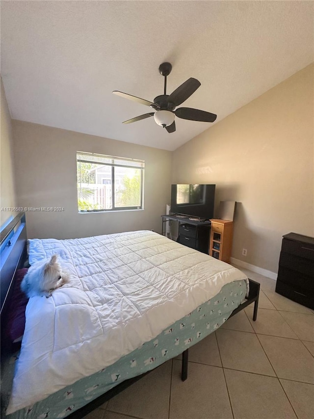 bedroom featuring ceiling fan, light tile patterned floors, and vaulted ceiling