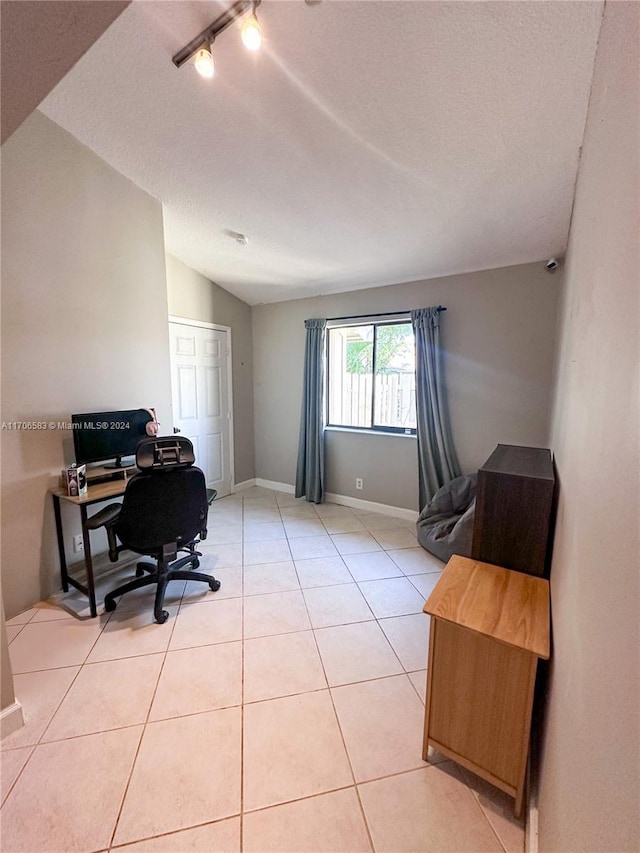 office area with light tile patterned floors, a textured ceiling, and vaulted ceiling