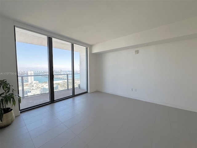 spare room with light tile patterned floors, a water view, and expansive windows