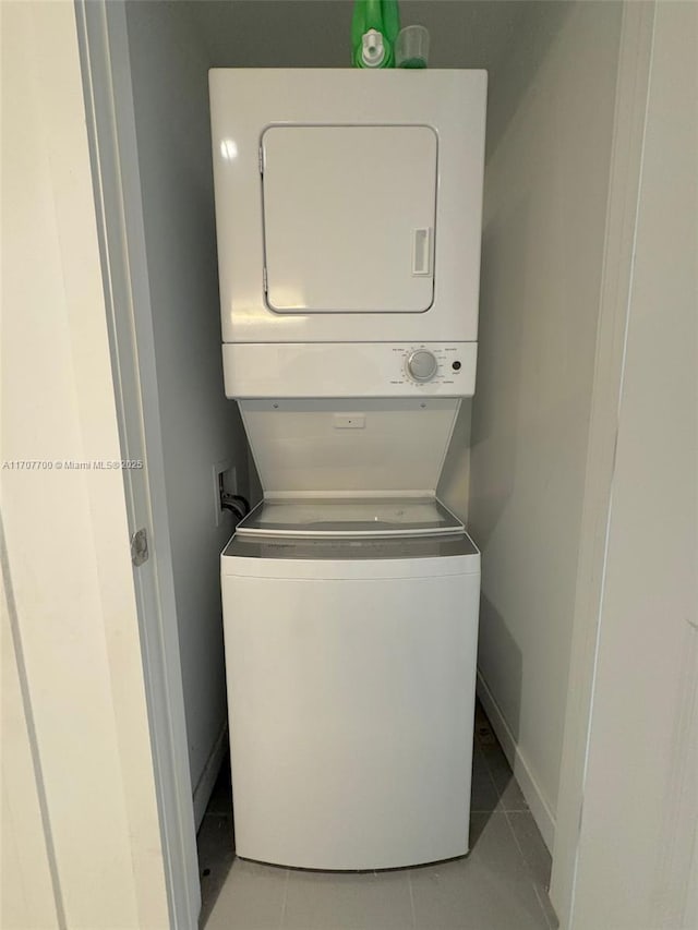 laundry area featuring light tile patterned floors and stacked washer and clothes dryer