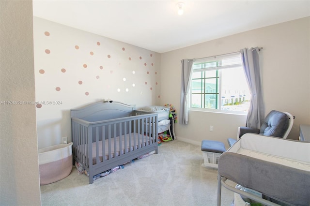 bedroom with light colored carpet and a nursery area