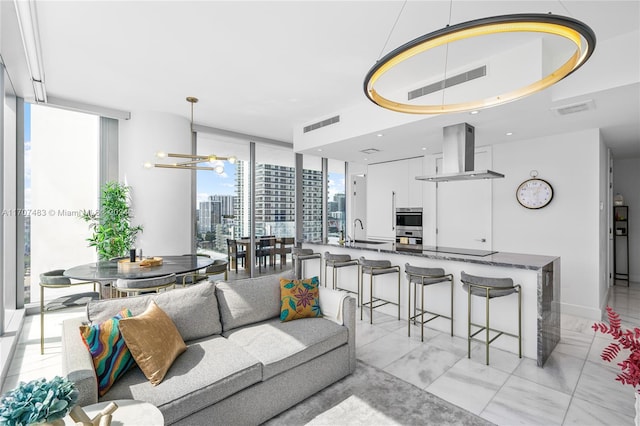 living room featuring sink, a notable chandelier, and a wall of windows