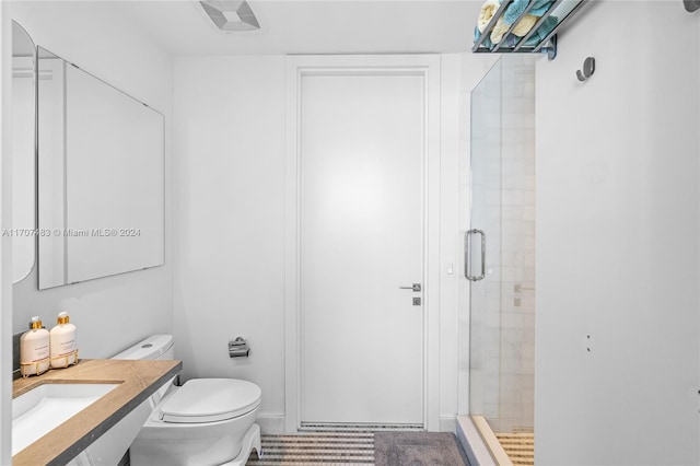 bathroom with sink, a shower with shower door, and toilet