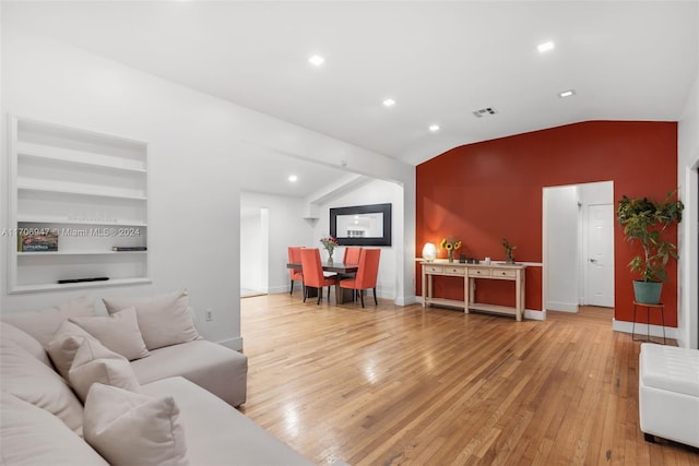 living room with built in features, hardwood / wood-style floors, and lofted ceiling