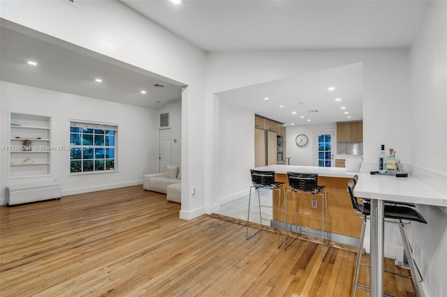 kitchen featuring lofted ceiling, light hardwood / wood-style floors, kitchen peninsula, and stainless steel refrigerator