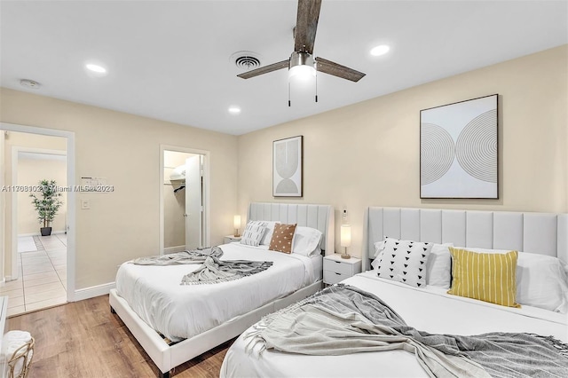 bedroom featuring hardwood / wood-style floors, ceiling fan, a walk in closet, and a closet