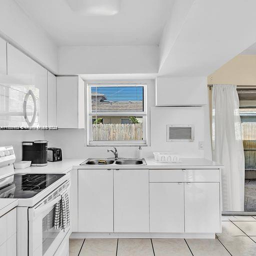 kitchen with sink, white cabinets, white appliances, and light tile patterned floors