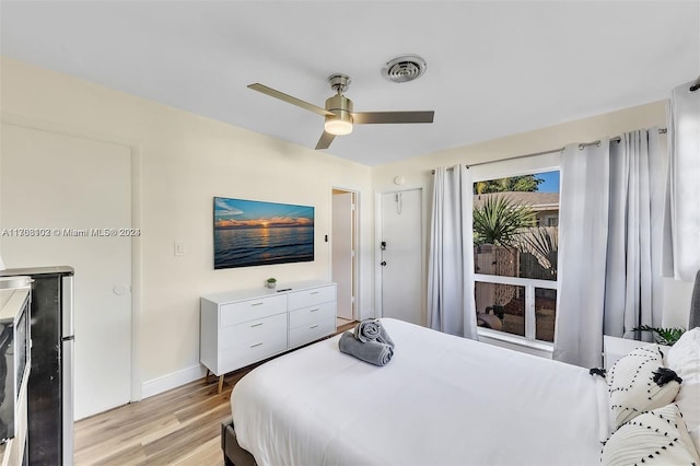 bedroom with ceiling fan, light hardwood / wood-style floors, and stainless steel refrigerator