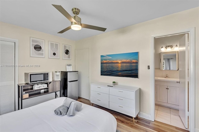 bedroom with ceiling fan, connected bathroom, light hardwood / wood-style floors, stainless steel refrigerator, and a closet