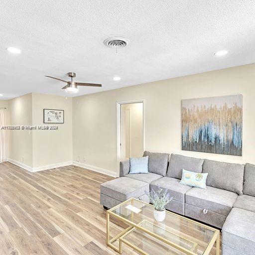 living room featuring hardwood / wood-style floors, a textured ceiling, and ceiling fan