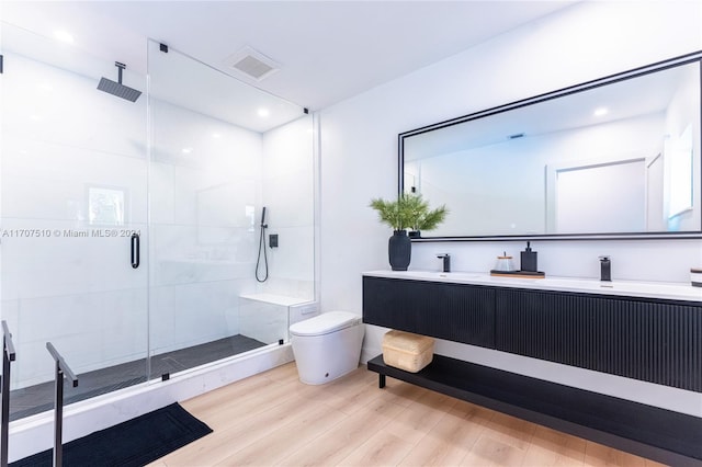 bathroom with hardwood / wood-style floors, vanity, toilet, and an enclosed shower