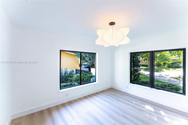 spare room with an inviting chandelier and light hardwood / wood-style flooring