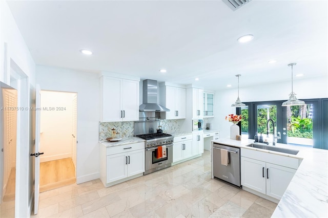 kitchen with white cabinets, wall chimney range hood, and appliances with stainless steel finishes