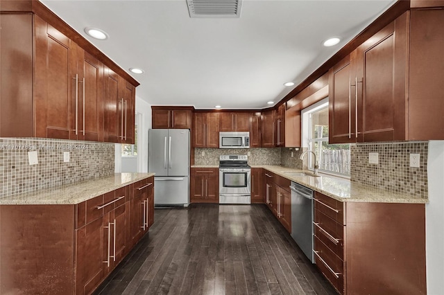 kitchen featuring sink, light stone countertops, tasteful backsplash, dark hardwood / wood-style flooring, and stainless steel appliances