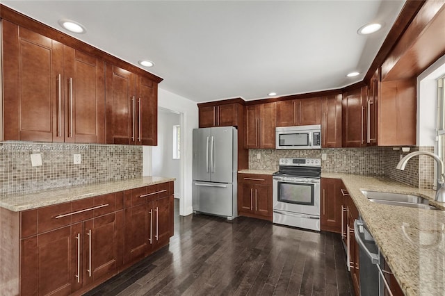 kitchen with light stone countertops, sink, dark wood-type flooring, stainless steel appliances, and backsplash