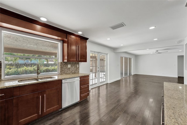 kitchen with light stone countertops, french doors, stainless steel dishwasher, dark wood-type flooring, and sink