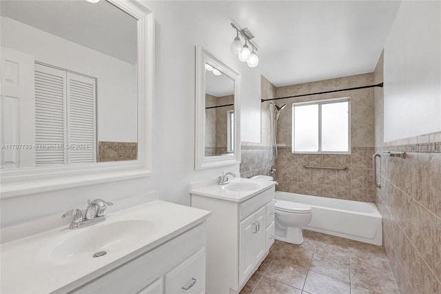 full bathroom with vanity, tiled shower / bath, tile patterned flooring, toilet, and tile walls