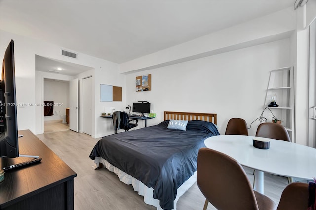 bedroom with light hardwood / wood-style floors and ensuite bathroom