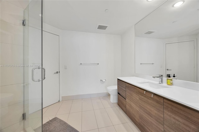 bathroom with tile patterned floors, vanity, a shower with shower door, and toilet