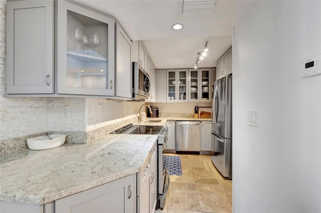 kitchen with light stone counters, sink, appliances with stainless steel finishes, and tasteful backsplash