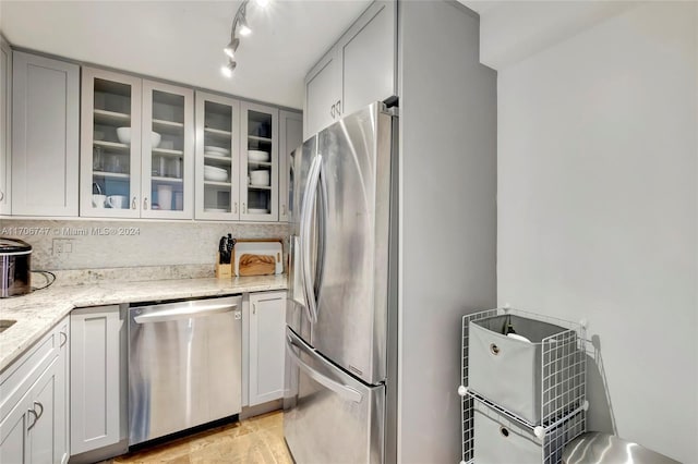 kitchen featuring backsplash, light stone counters, and stainless steel appliances