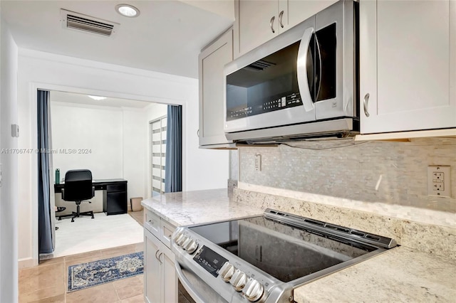 kitchen with tasteful backsplash, light stone counters, light tile patterned floors, and stainless steel appliances