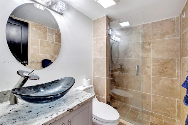 bathroom with vanity, toilet, and a shower with door