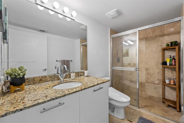 bathroom featuring tile patterned flooring, vanity, a shower with shower door, and toilet