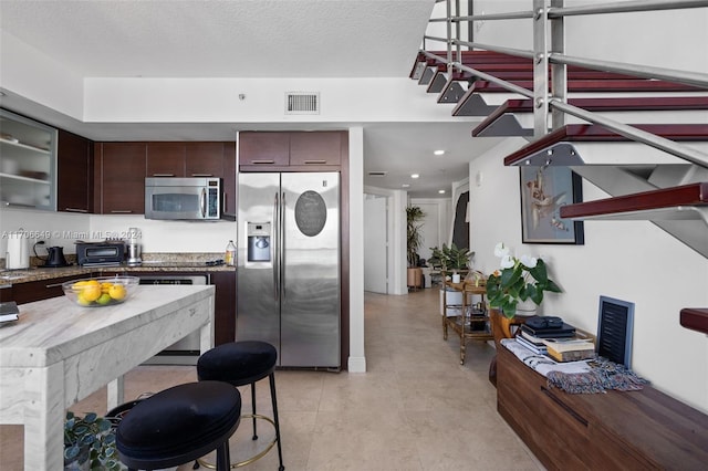 kitchen featuring dark brown cabinets, a textured ceiling, and appliances with stainless steel finishes