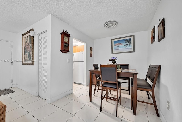 dining room with a textured ceiling and light tile patterned floors