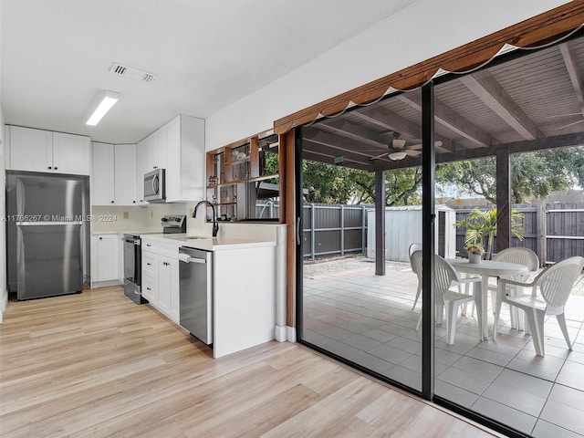 kitchen with white cabinets, ceiling fan, appliances with stainless steel finishes, and light hardwood / wood-style flooring