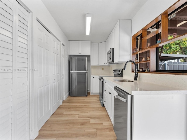 kitchen with white cabinetry, light hardwood / wood-style flooring, sink, and appliances with stainless steel finishes