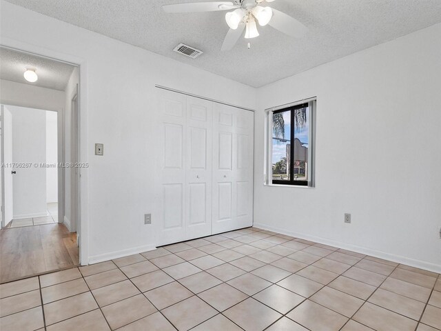 unfurnished room with ceiling fan, light tile patterned flooring, and a textured ceiling