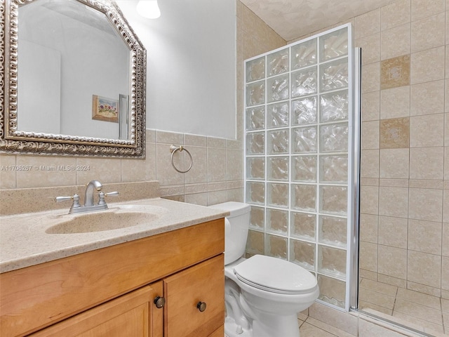 bathroom with vanity, toilet, tile walls, and a shower with shower door